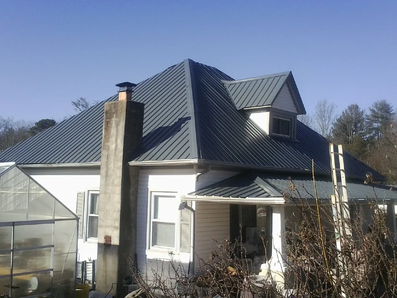 Dark blue standing seam metal roof on a white farmhouse with dormer — Slate & Tile Roof Repair by Roofing Brothers in Whitinsville