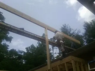 Carpenter setting a ridge beam over a new addition frame — Ice Dam Removal by Roofing Brothers in Whitinsville