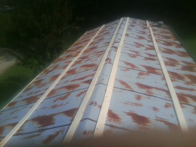 Rusted metal roof panels with new wood purlins before replacement — Storm Damage Roof Repair in Whitinsville by Roofing Brothers