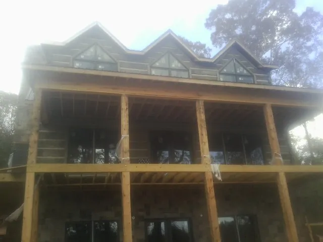 Dormers and porch framing on a large log home under construction — Roof Coating work by our crew in Whitinsville