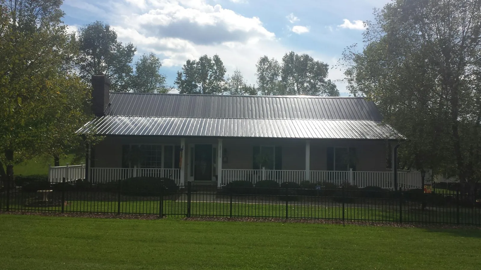 Gray metal roof on a brick ranch with a full width front porch — Gutter Guard Installation work by our crew in Whitinsville