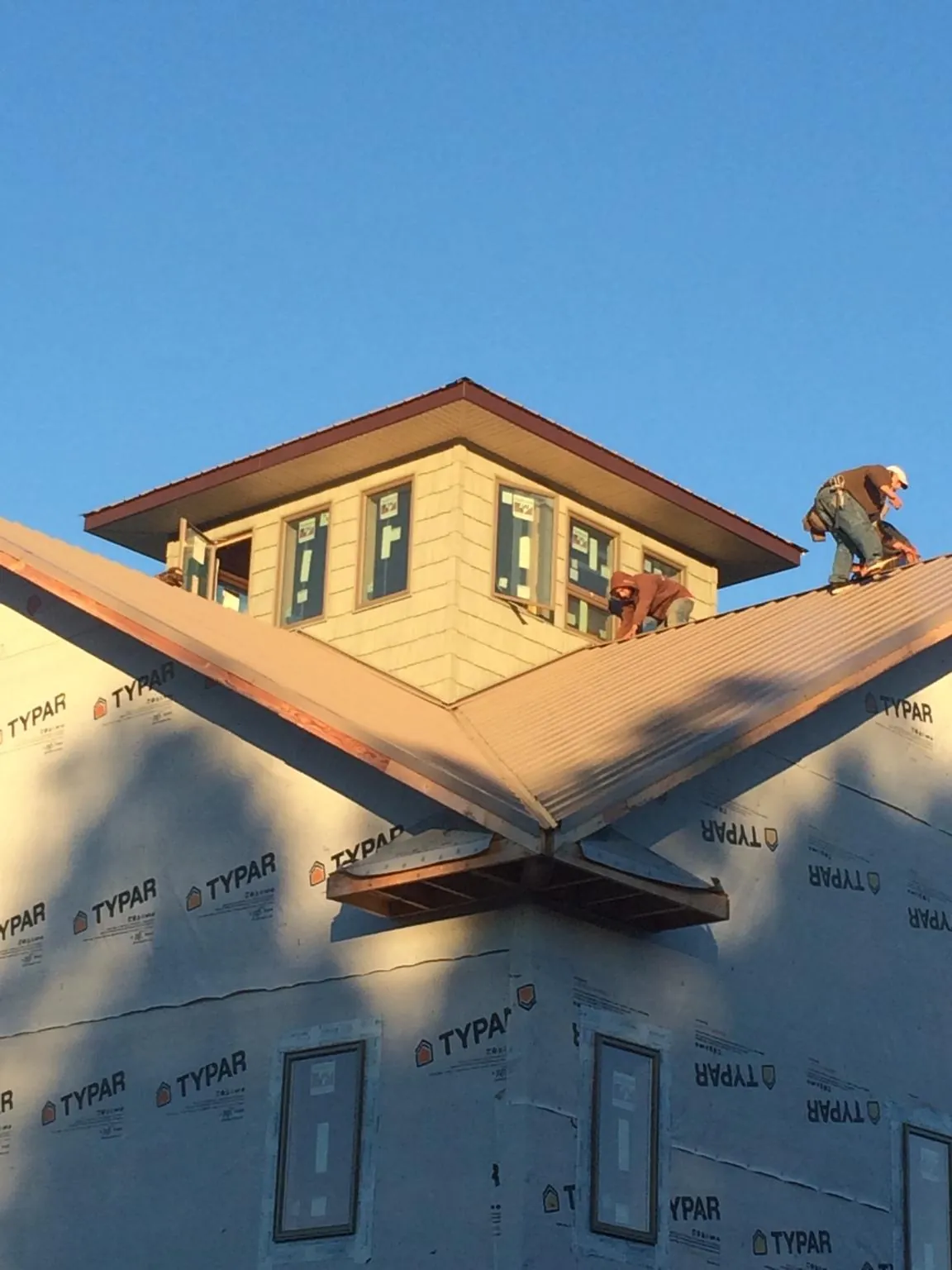 Roofers working around a rooftop cupola on a new metal roof at sunset — Roof Waterproofing in Whitinsville by Roofing Brothers